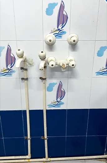 Dull stained bathroom wall tiles around taps and a shower fitting before cleaning, and the same wall tiles clean and bright with the chrome polished