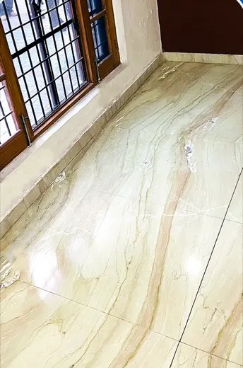 Dull marble floor with dirt along the skirting before cleaning, and the same marble floor cleaned and brightened
