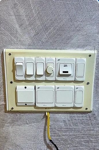 Electrical switchboard with yellowed grimy switch plates before cleaning, and the same switchboard with the plates cleaned